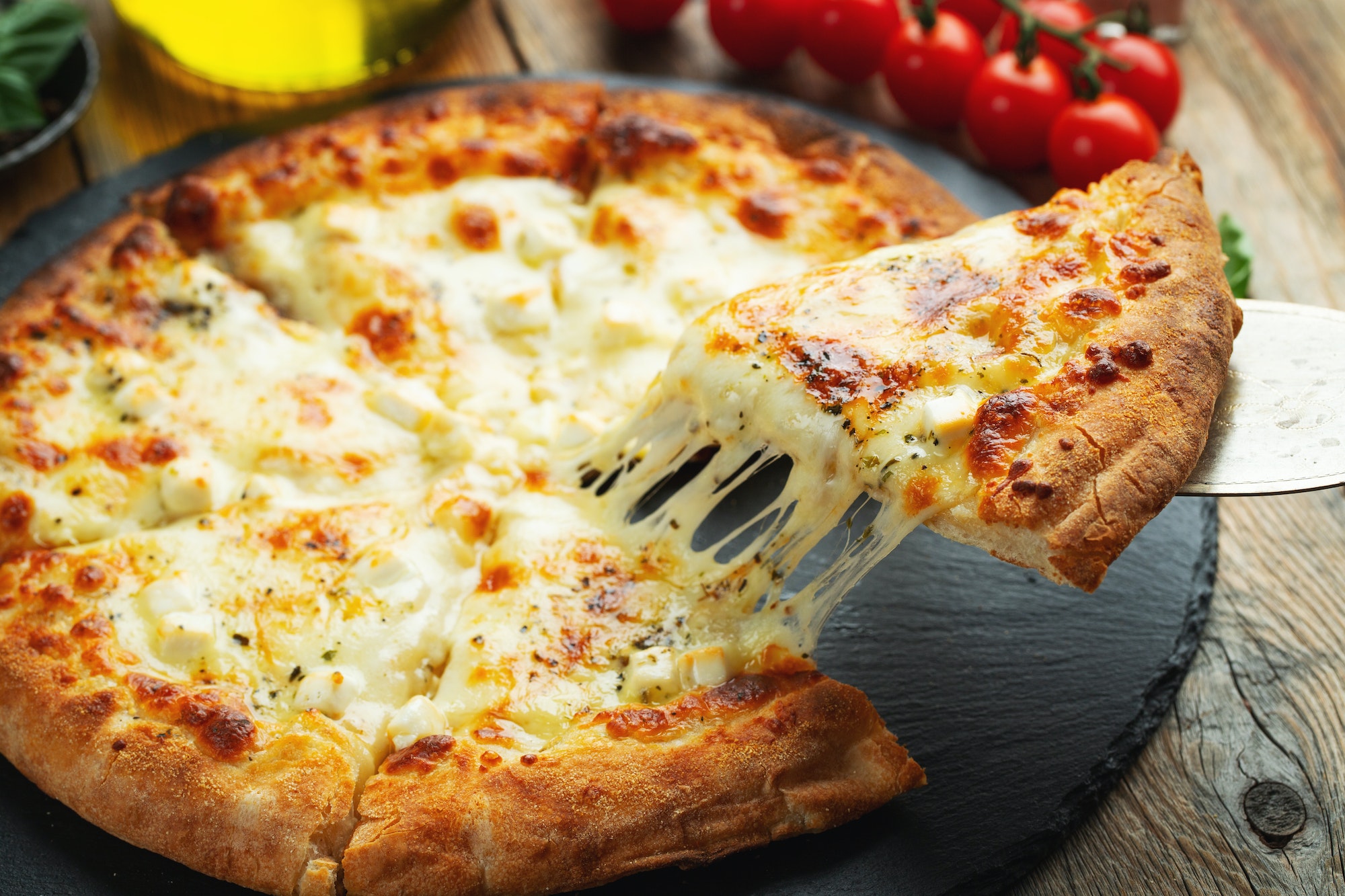 A slice of hot Italian pizza with stretching cheese. Pizza four cheeses with basil.