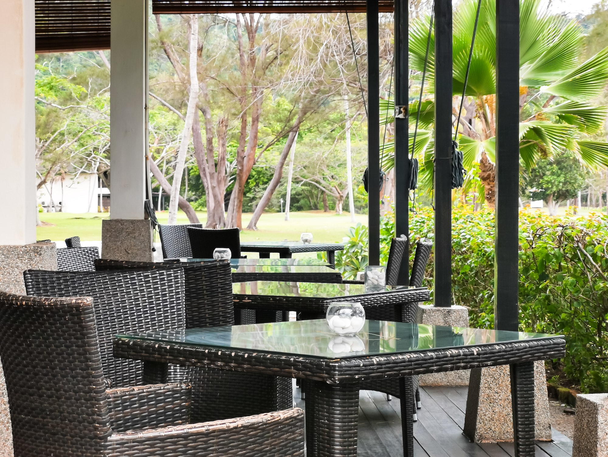 Empty dining chairs and tables at an open air restuarant.